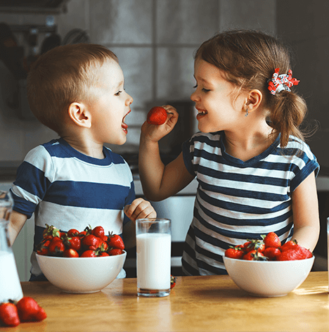 siblings feeding each other strawberries